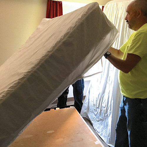 A technician installs a bed bug cover on a mattress.